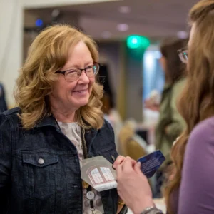 Two women smiling and interacting at a conference