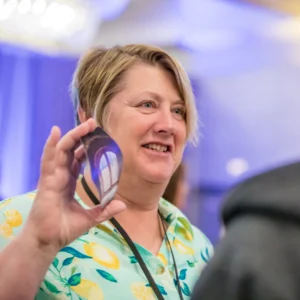 A woman holds up a card smiling and interacting at a conference