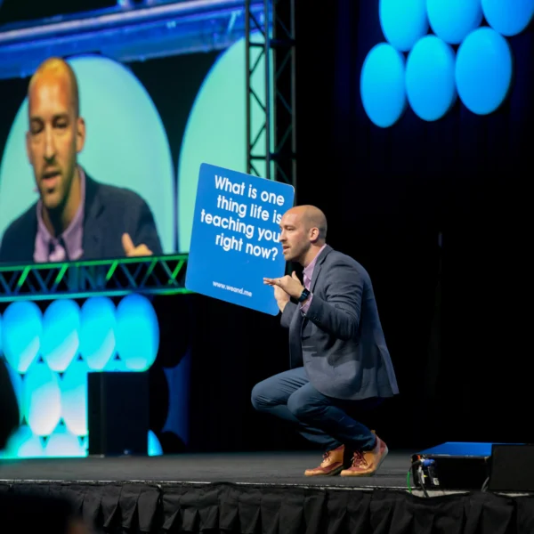 Chad speaking during a fun, interactive keynote holding a giant We Connect Card